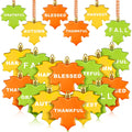Collection of 24 Thanksgiving maple leaf hanging ornaments in green, orange, and yellow, each with a different word like Grateful, Blessed, Harvest, Fall, Autumn, Thankful.