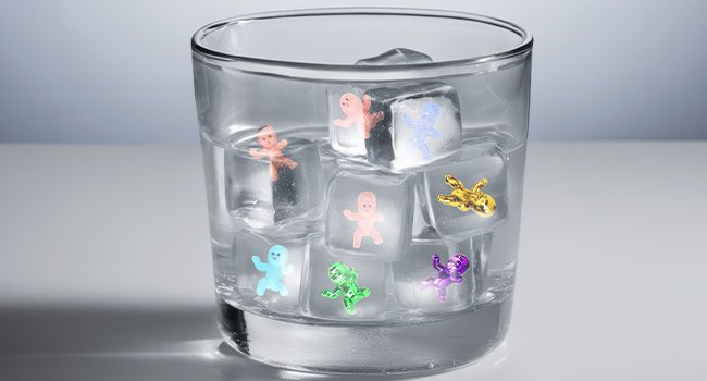 Clear glass filled with ice cubes and colorful plastic king cake babies inside.