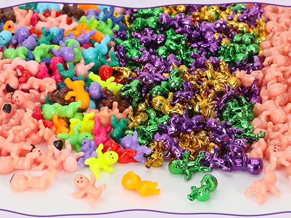 Pile of colorful plastic king cake babies in purple, gold, green, and pink, some with metallic sheen.