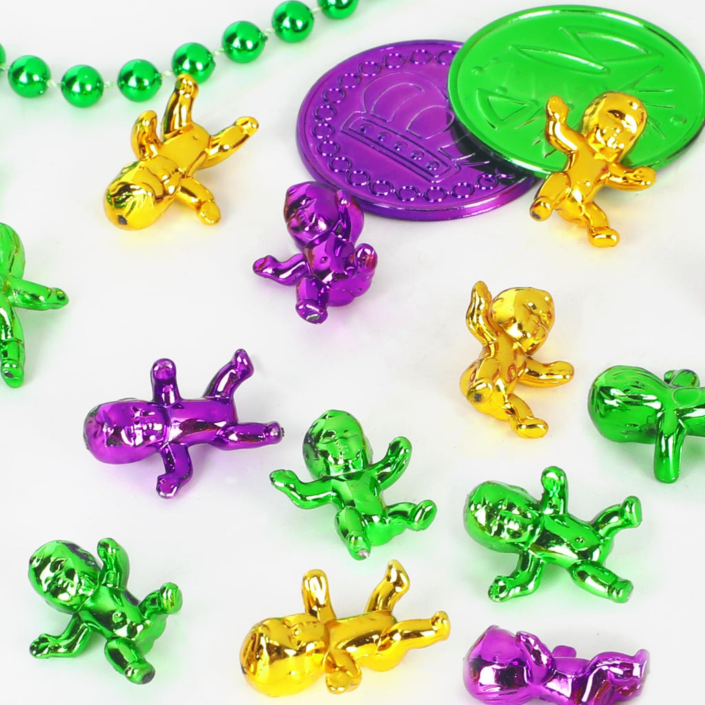 Collection of shiny plastic king cake babies in purple, green, and gold, with Mardi Gras beads and coins.