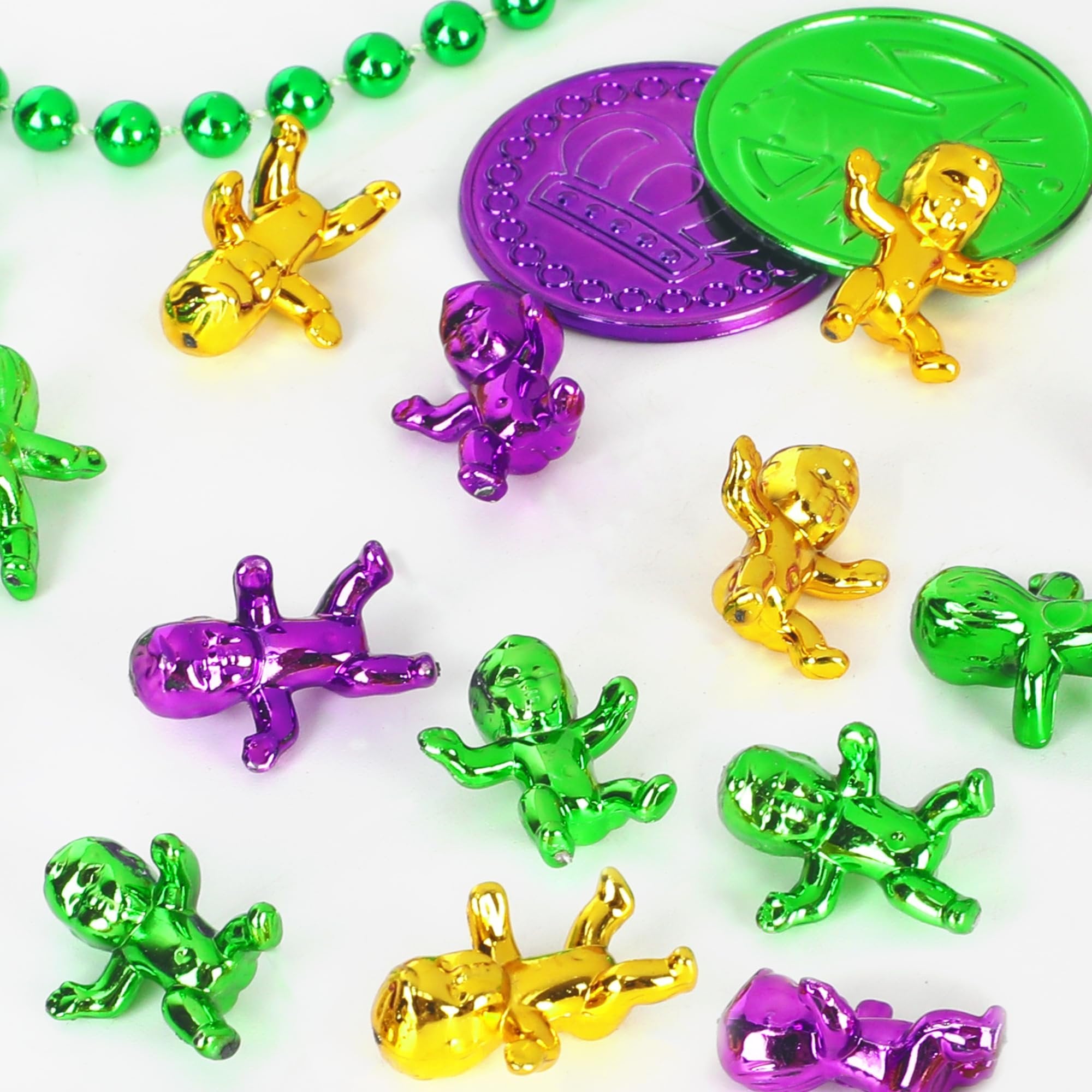 Collection of shiny plastic king cake babies in purple, green, and gold, with Mardi Gras beads and coins.