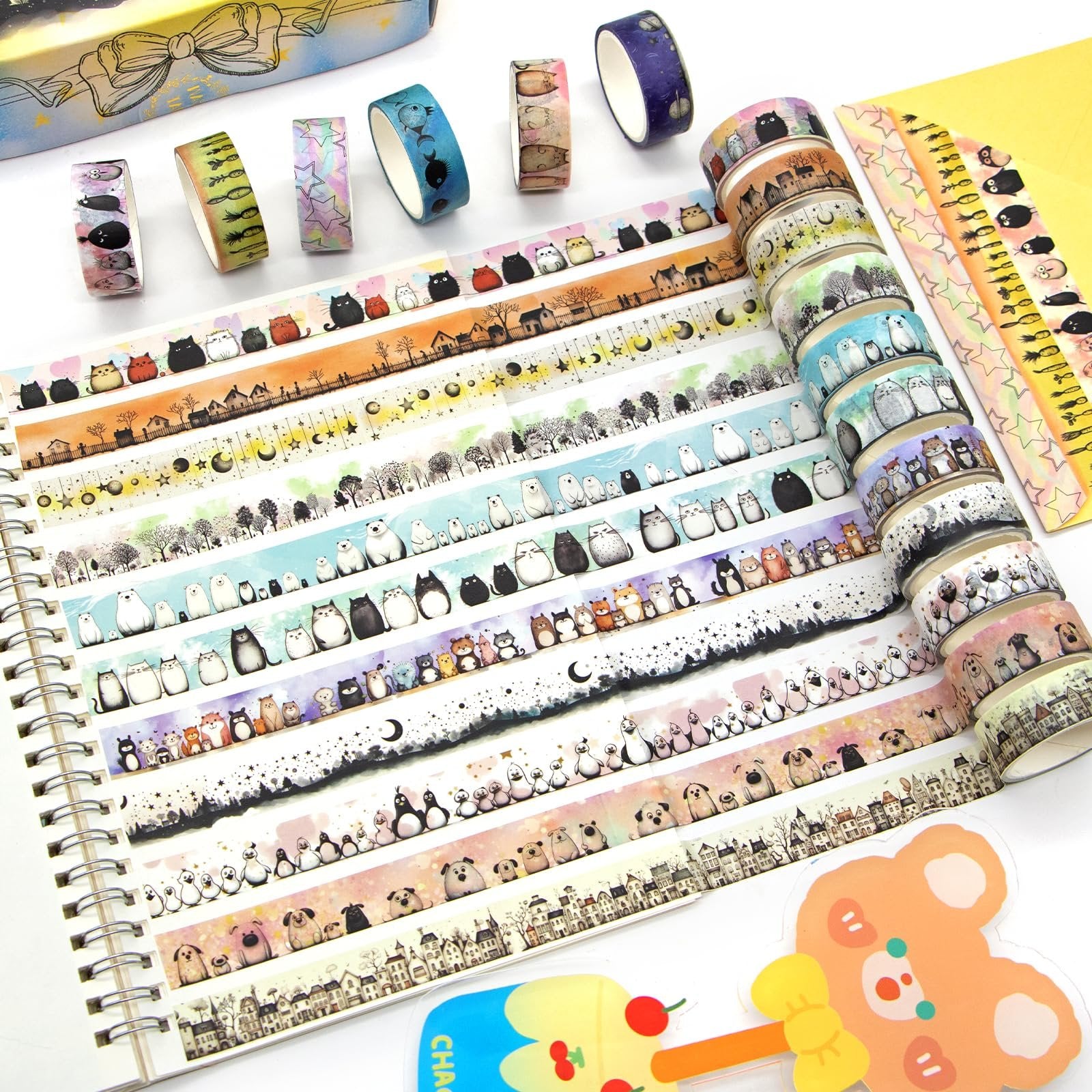 Collection of kawaii animal and landscape patterned washi tape rolls laid out on a spiral notebook.