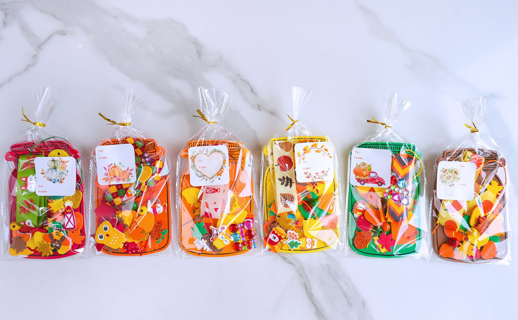 Six fall-themed craft kits in clear bags, each containing foam shapes, stickers, and embellishments for mason jar ornaments.
