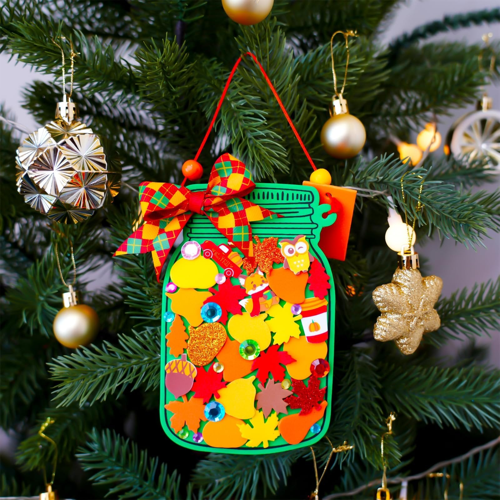 Fall mason jar ornament craft kit decoration hanging on a Christmas tree with autumn leaves and owl stickers.