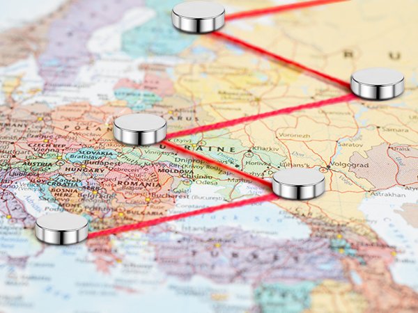 Silver magnetic push pins placed on a map of Europe, connected by red lines.