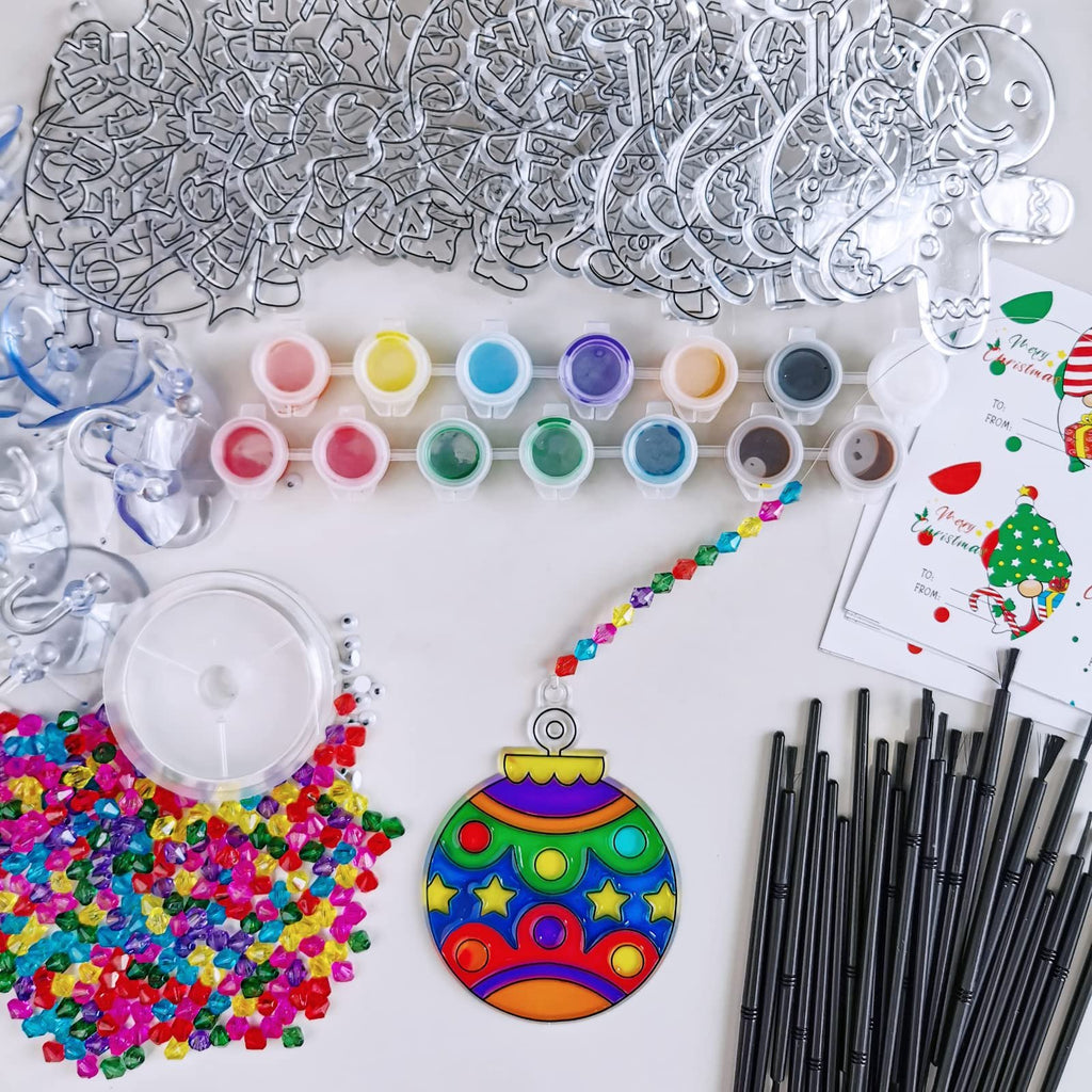 Christmas suncatcher craft kit contents including clear ornaments, paints, beads, brushes, and gift tags.