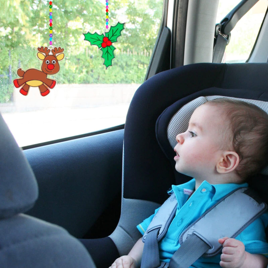 Baby in car seat looking at Christmas suncatchers hanging on window