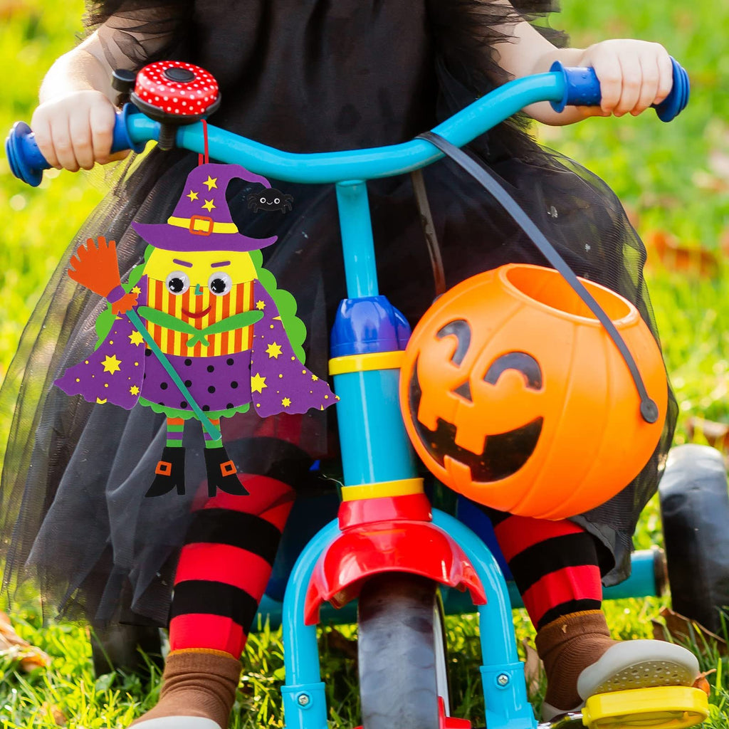 Child in Halloween costume on a tricycle holding a witch craft ornament and a pumpkin bucket