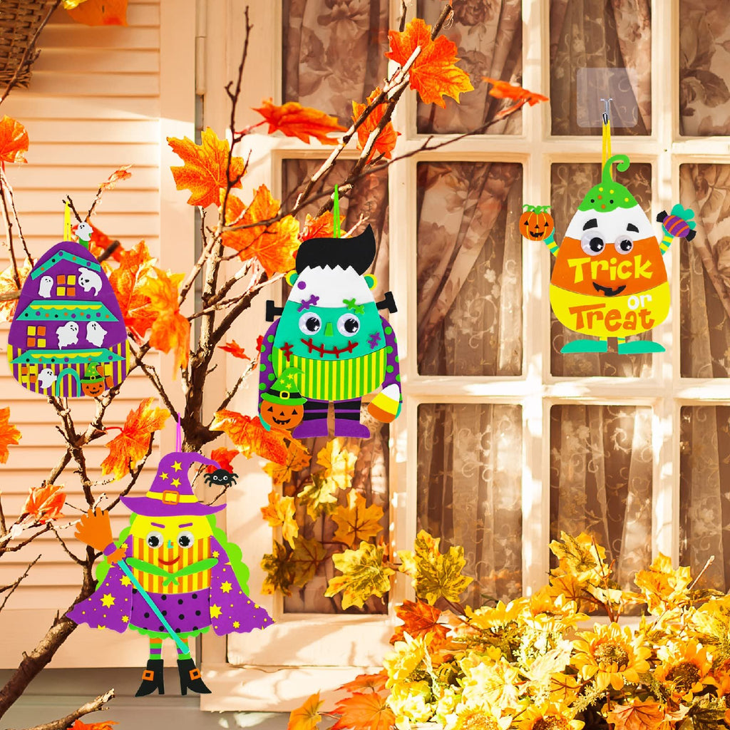 Halloween foam ornaments of a witch, Frankenstein, and candy corn hanging on branches with autumn leaves.