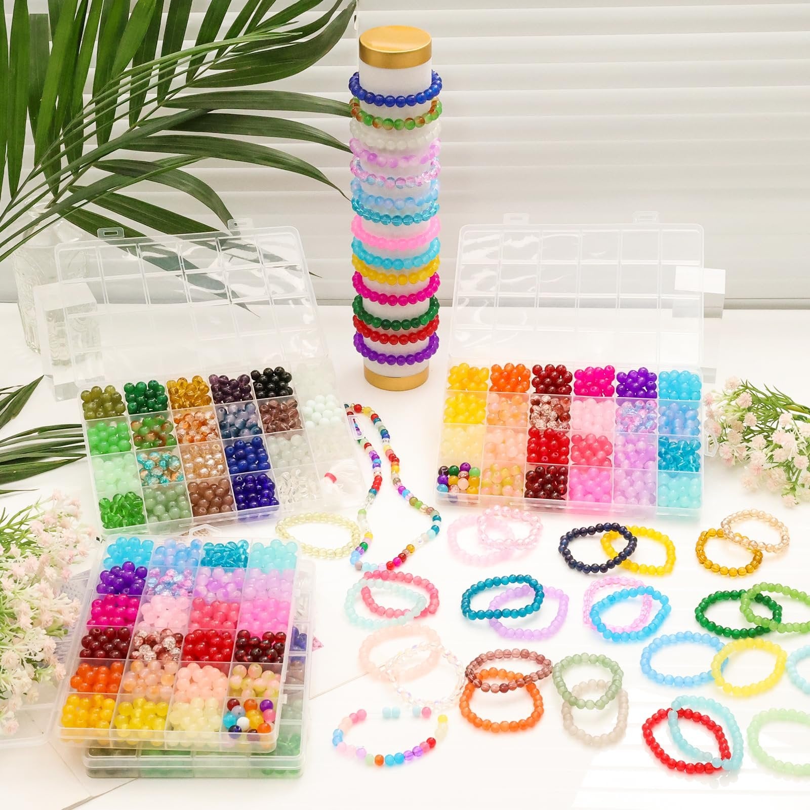 Bracelet making kit with multiple compartments filled with colorful glass beads and finished bracelets.