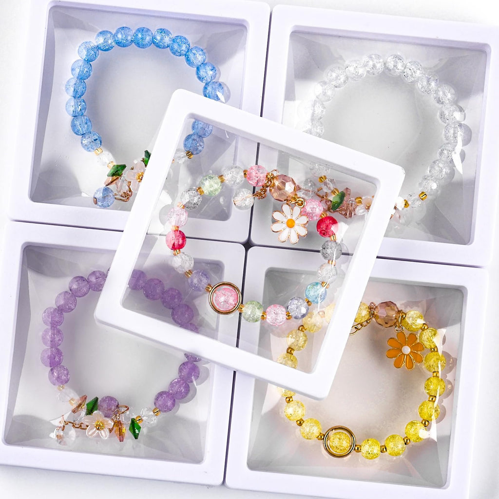 Four colorful beaded bracelets displayed in white square boxes, one central bracelet with flower charms.