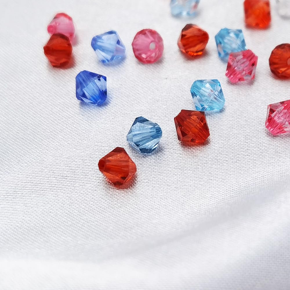 Scattered 6mm faceted bicone acrylic beads in red, blue, and pink on a white satin background.
