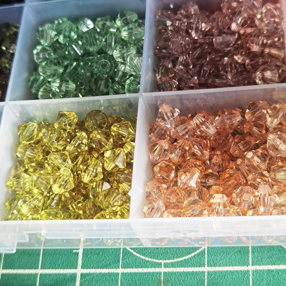 Four compartments of faceted acrylic bicone beads in green, pink, yellow, and orange.