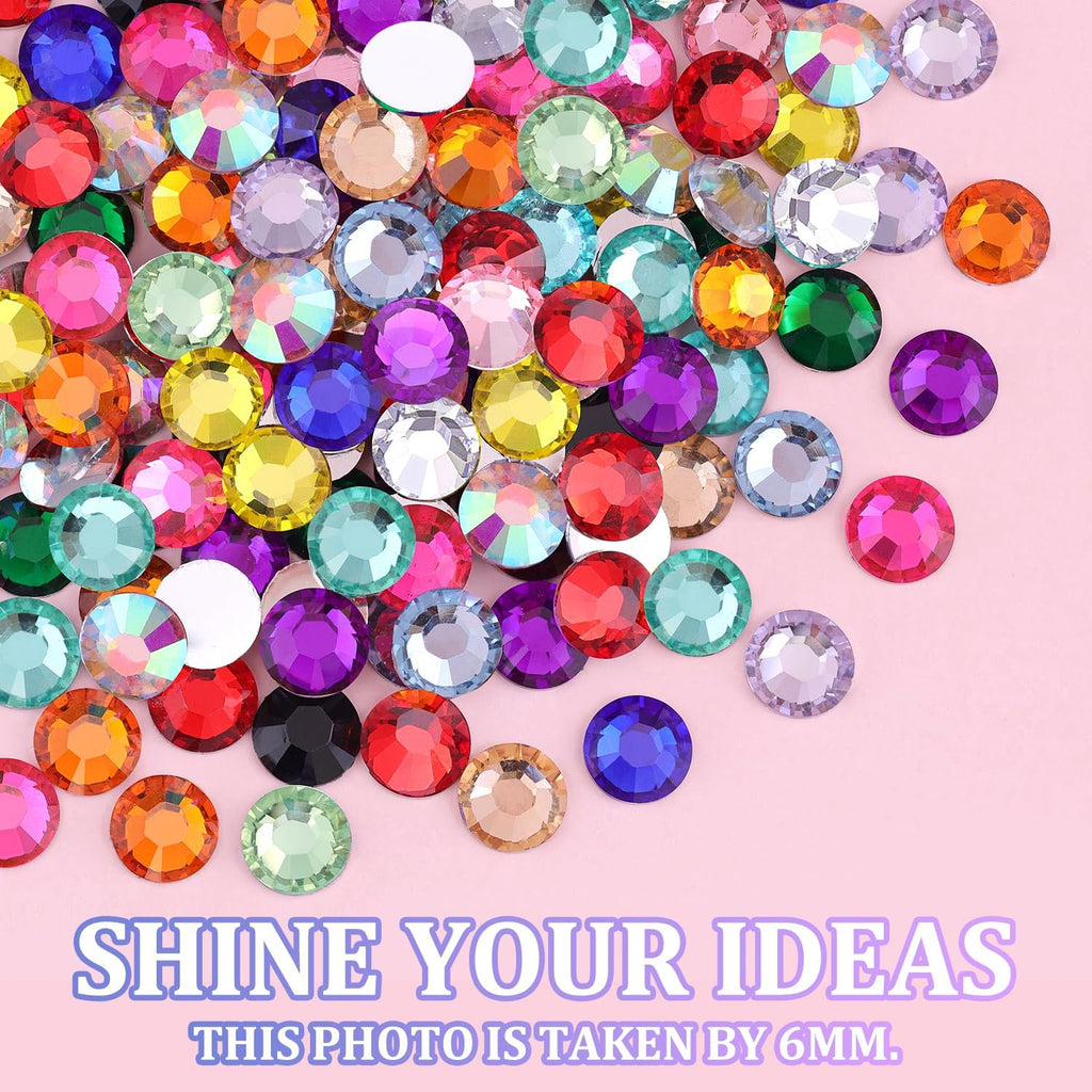 Assortment of colorful 3mm resin rhinestones scattered on a pink background.
