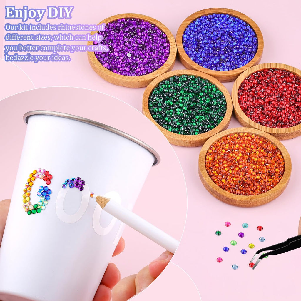 Close-up of a hand decorating a white cup with colorful rhinestones from a kit, with bowls of rhinestones in the background.