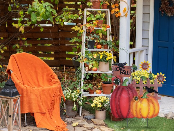 Decorative metal garden stakes with pumpkins, sunflowers, crows, and an 'I LOVE FALL' sign, set in an autumn yard.