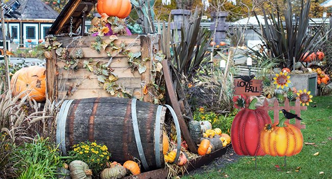 Decorative metal fall garden stakes with pumpkins, sunflowers, crows, and 'I LOVE FALL' sign in a yard setting.
