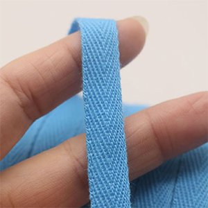 Close-up of a light blue cotton twill tape with a herringbone weave, held by fingers.
