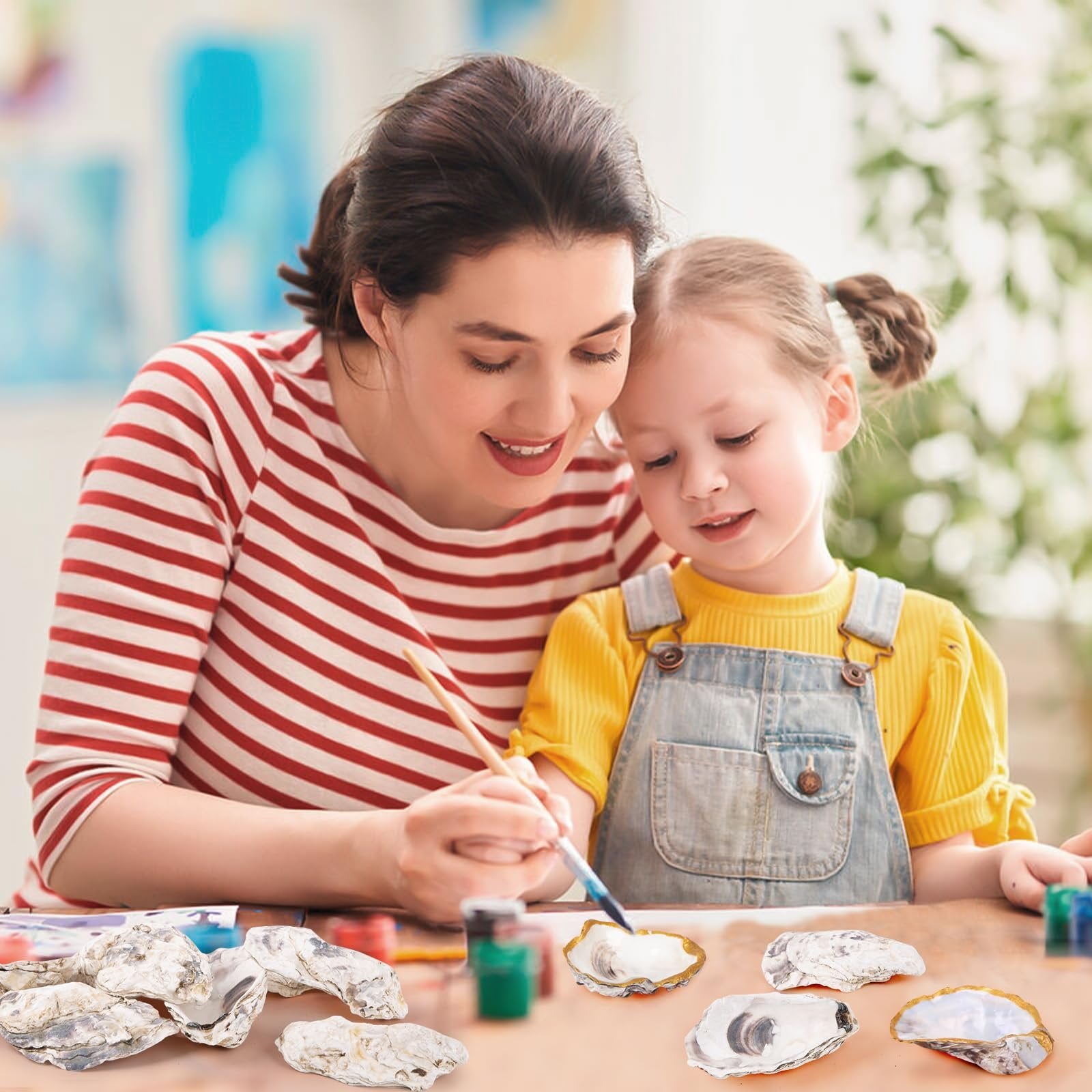 Mother and daughter painting natural oyster shells on a table with art supplies