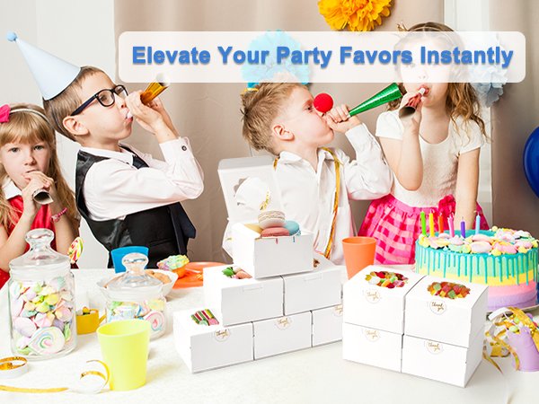 Children at a party blowing horns around a table with treat boxes and a cake. White boxes are stacked and filled with colorful candies.