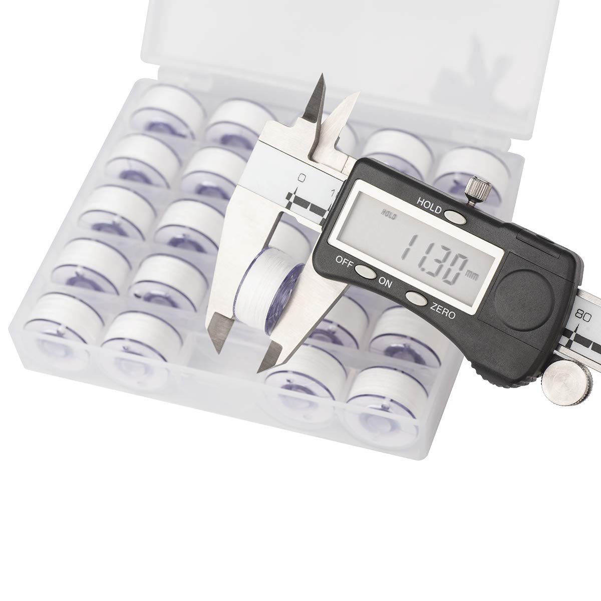 Digital caliper measuring a white prewound bobbin thread in a clear storage case with multiple bobbins.