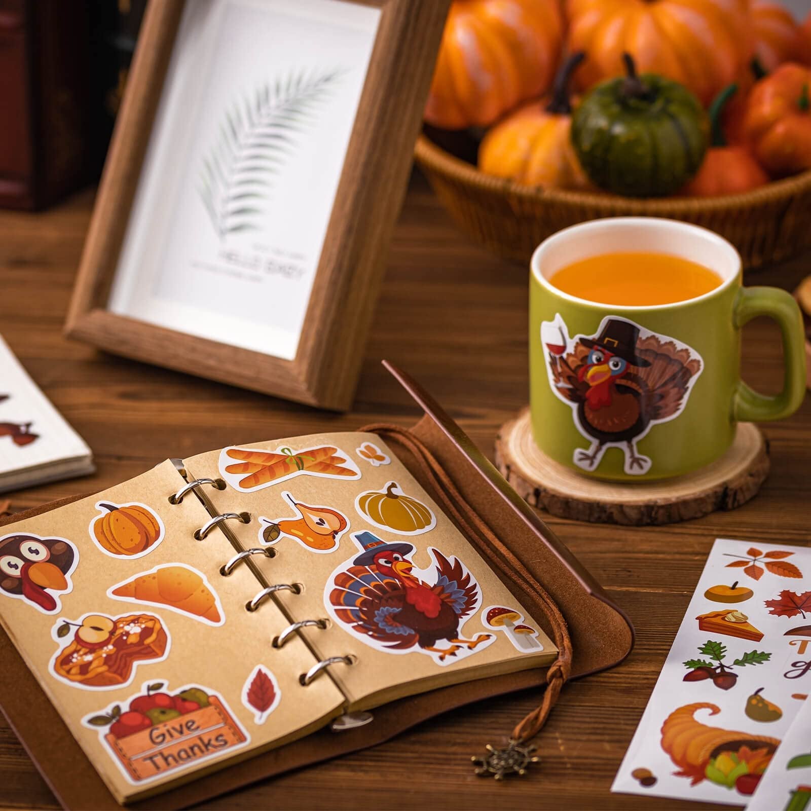 Autumn stickers with pumpkins, turkeys, and leaves scattered on a notebook and mug.
