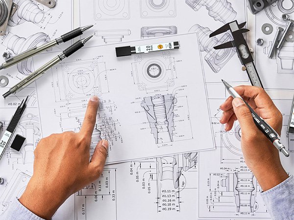 Hands pointing at technical drawings with mechanical pencils and calipers, showing engineering design process.