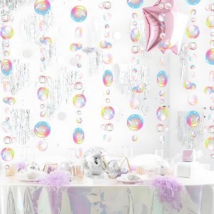 Transparent bubble garland with iridescent pink star balloon and silver fringe curtains hanging above a decorated table.