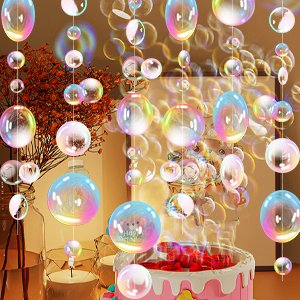 Transparent bubble garland with iridescent spheres hanging over a decorated cake and candle.
