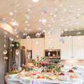 Transparent bubble garland with iridescent bubbles hanging over a party food spread in a kitchen.