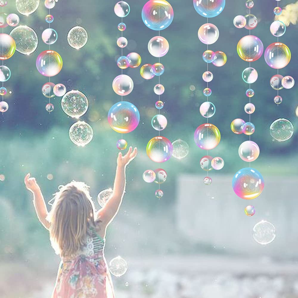 Girl reaching up towards hanging iridescent bubble garland decorations outdoors