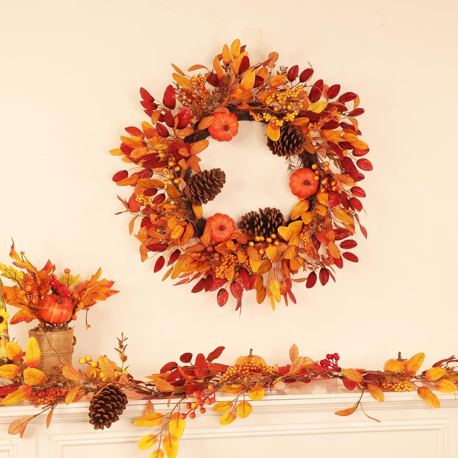 Foldable fall wreath with pumpkins, pinecones, berries, and eucalyptus leaves displayed above a mantel with matching garland.