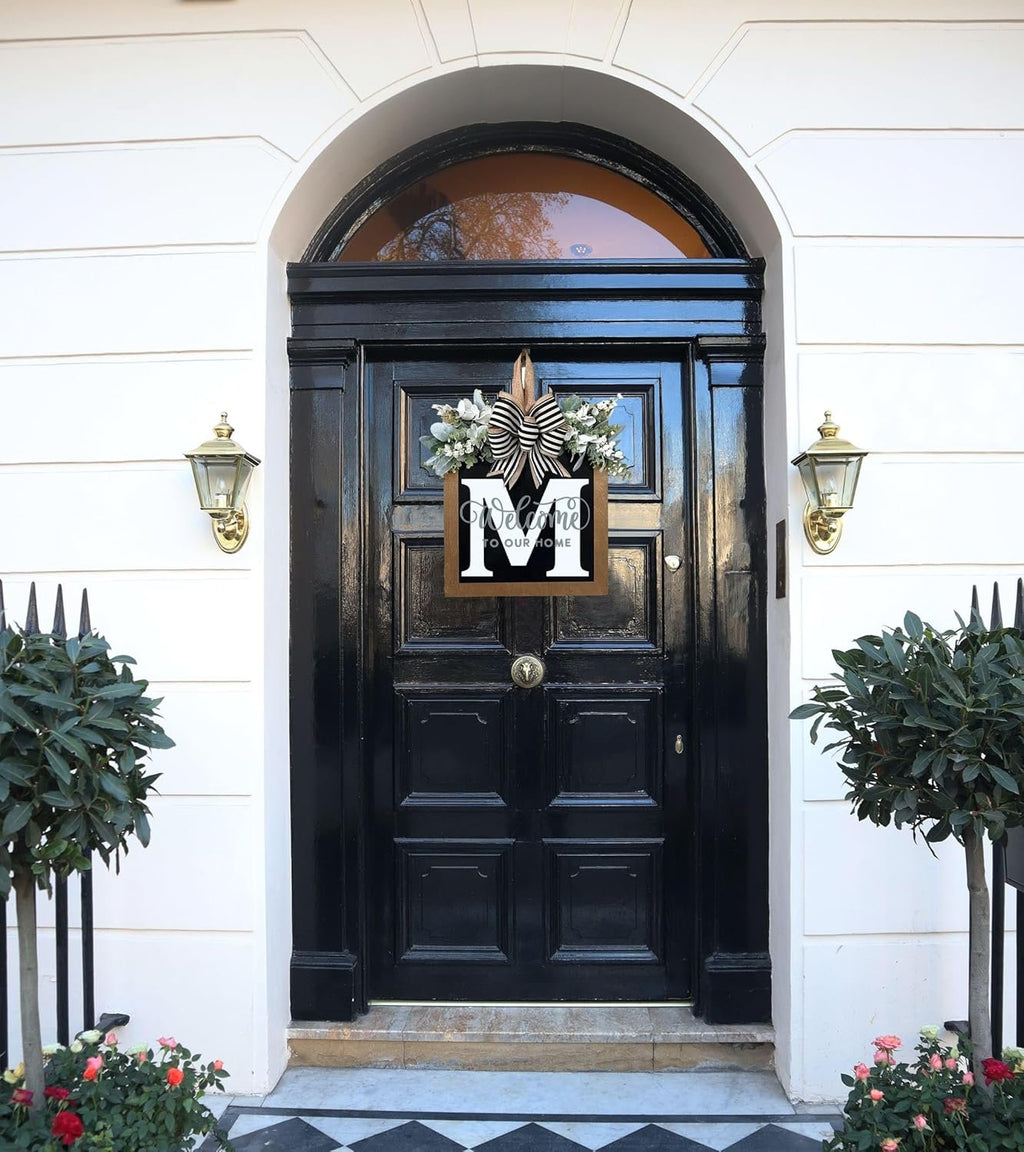 Front door decorated with a monogram wreath featuring eucalyptus garland and a bow.