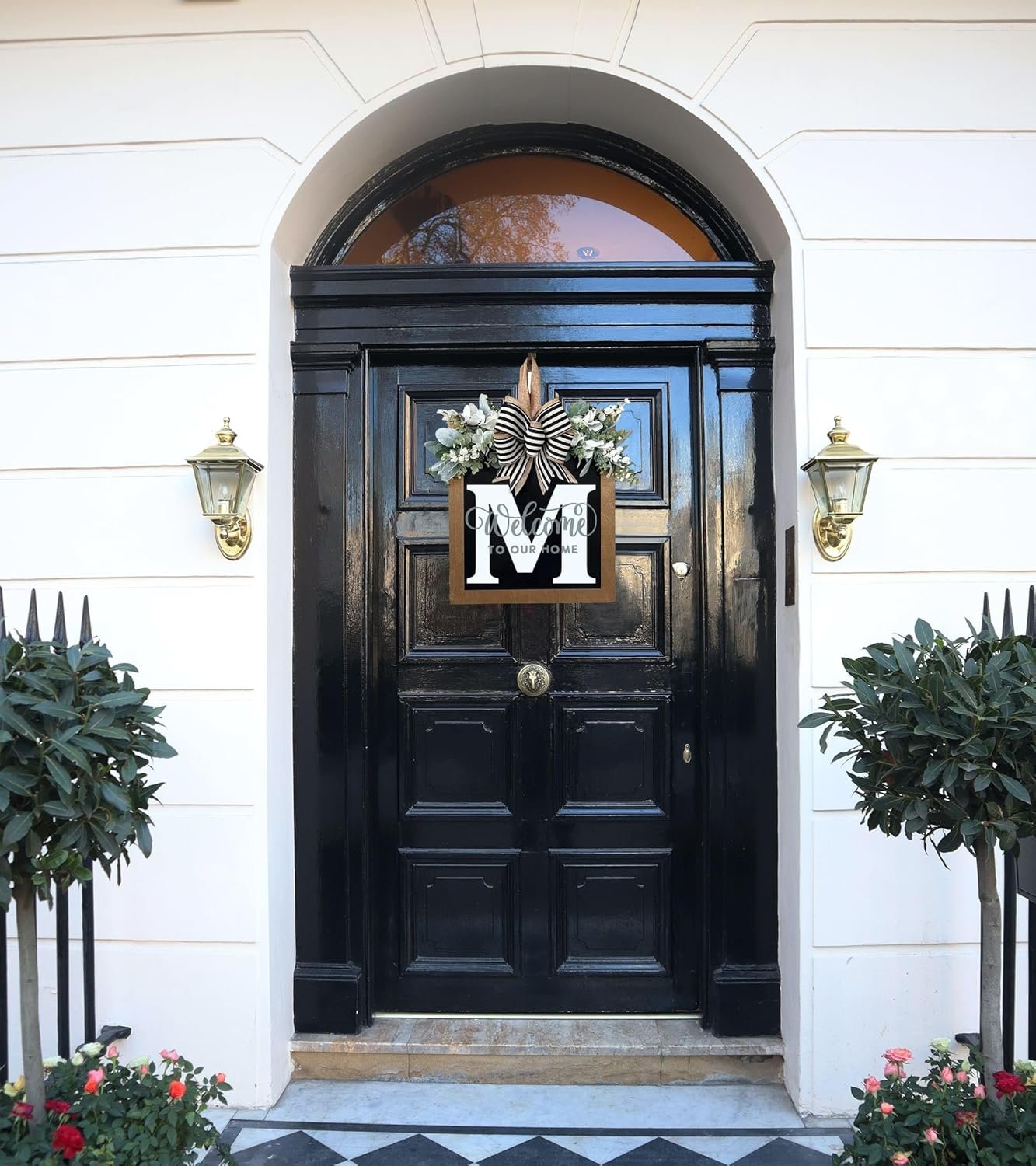Front door decorated with a monogram wreath featuring eucalyptus garland and a bow.