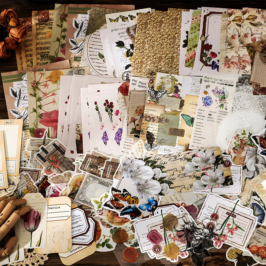 Flat lay of vintage floral and butterfly themed scrapbooking paper sheets, stickers, and tags.