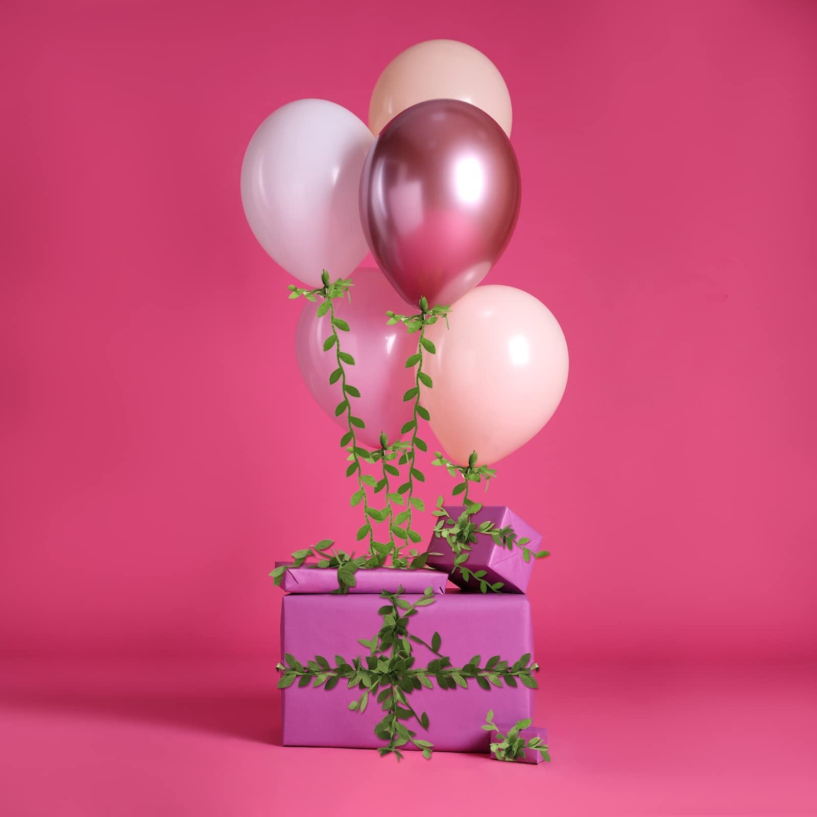 Artificial leaf vine ribbon wrapped around purple gift boxes with balloons floating above