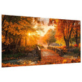 Wooden bridge covered in autumn leaves with a stream and sunbeams through trees.