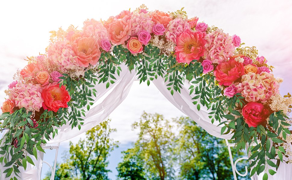 Wedding arch decorated with pink and coral flowers and green foliage, draped with white fabric.