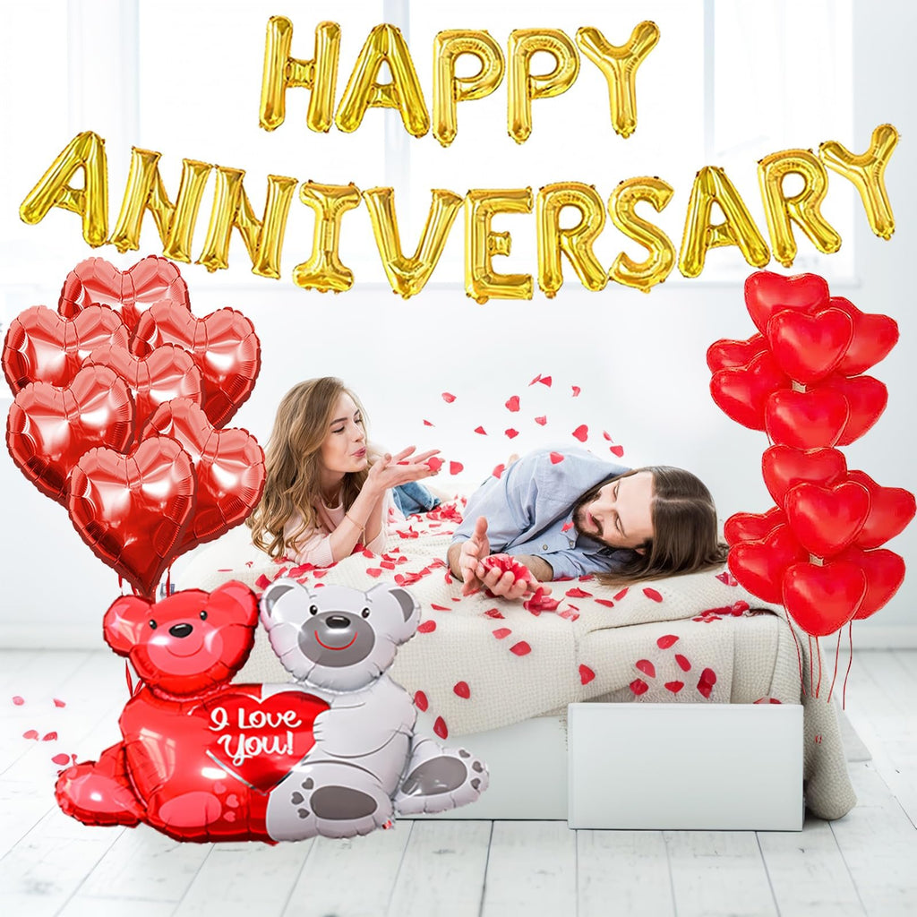 Couple in bed surrounded by anniversary balloons and rose petals, one blowing kisses