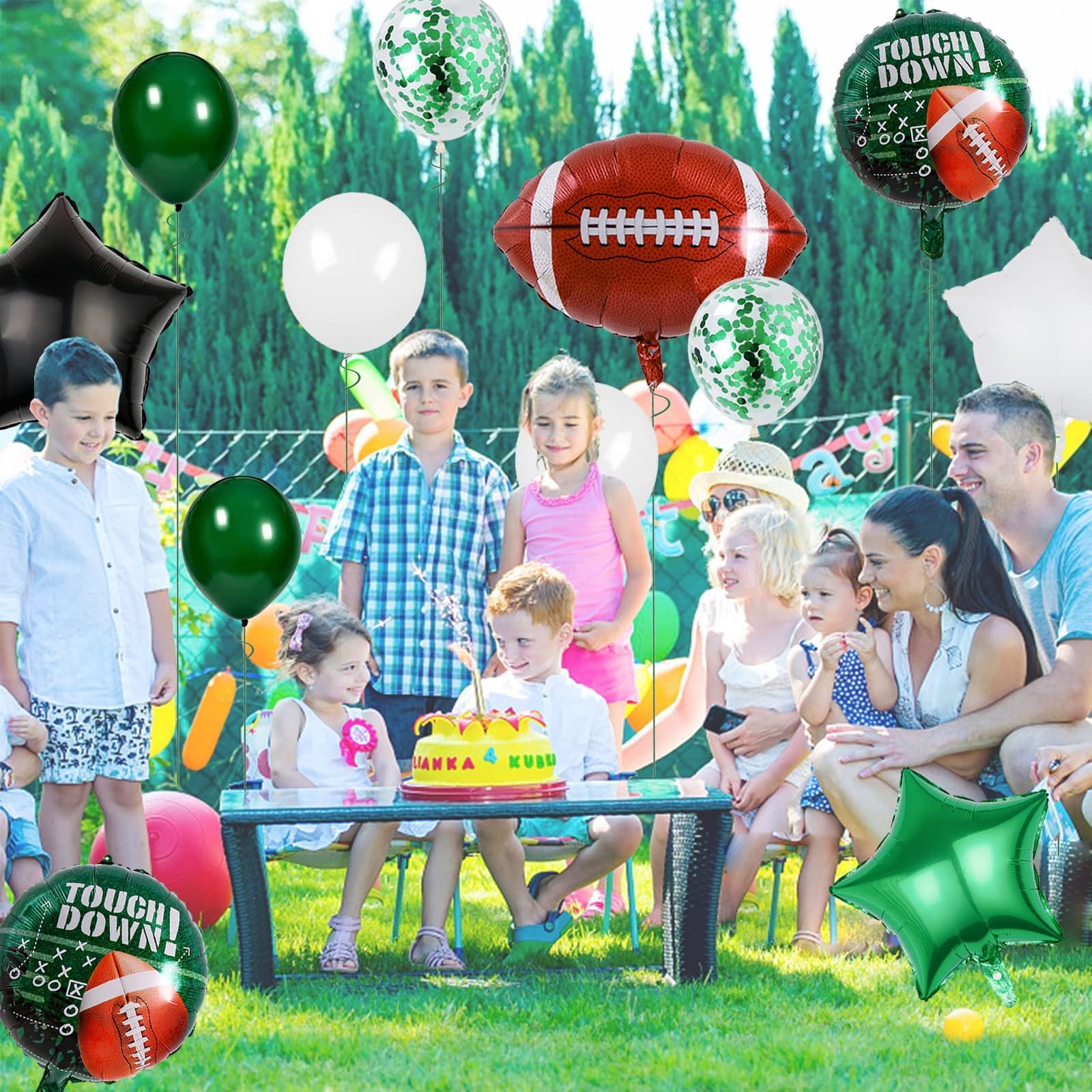 Family and children celebrating a birthday outdoors with football-themed balloons and a cake.