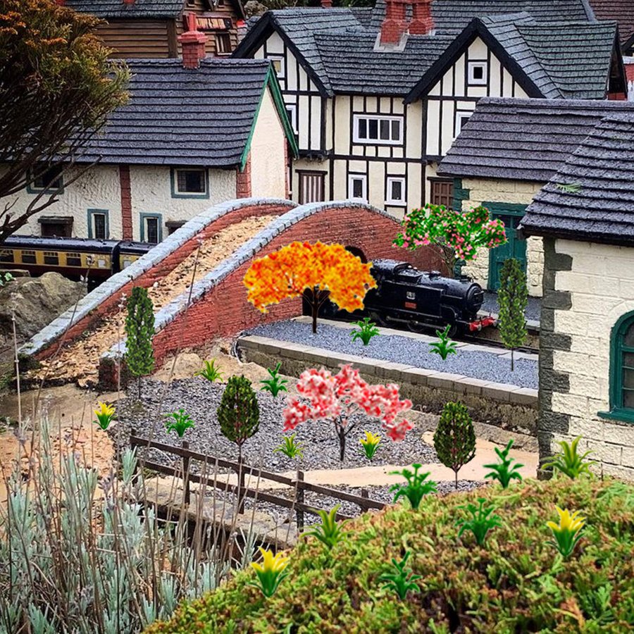 Miniature village scene with a train on tracks, a brick bridge, and various model trees and houses.
