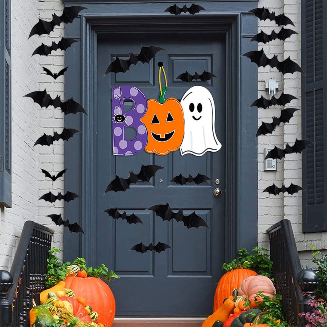 Halloween door decorations with black bat decals and a 'BOO' sign featuring a pumpkin and ghost, surrounded by pumpkins on the porch.