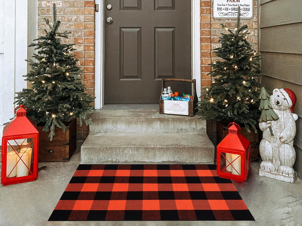Orange and black buffalo plaid rug on a porch with Christmas trees and lanterns