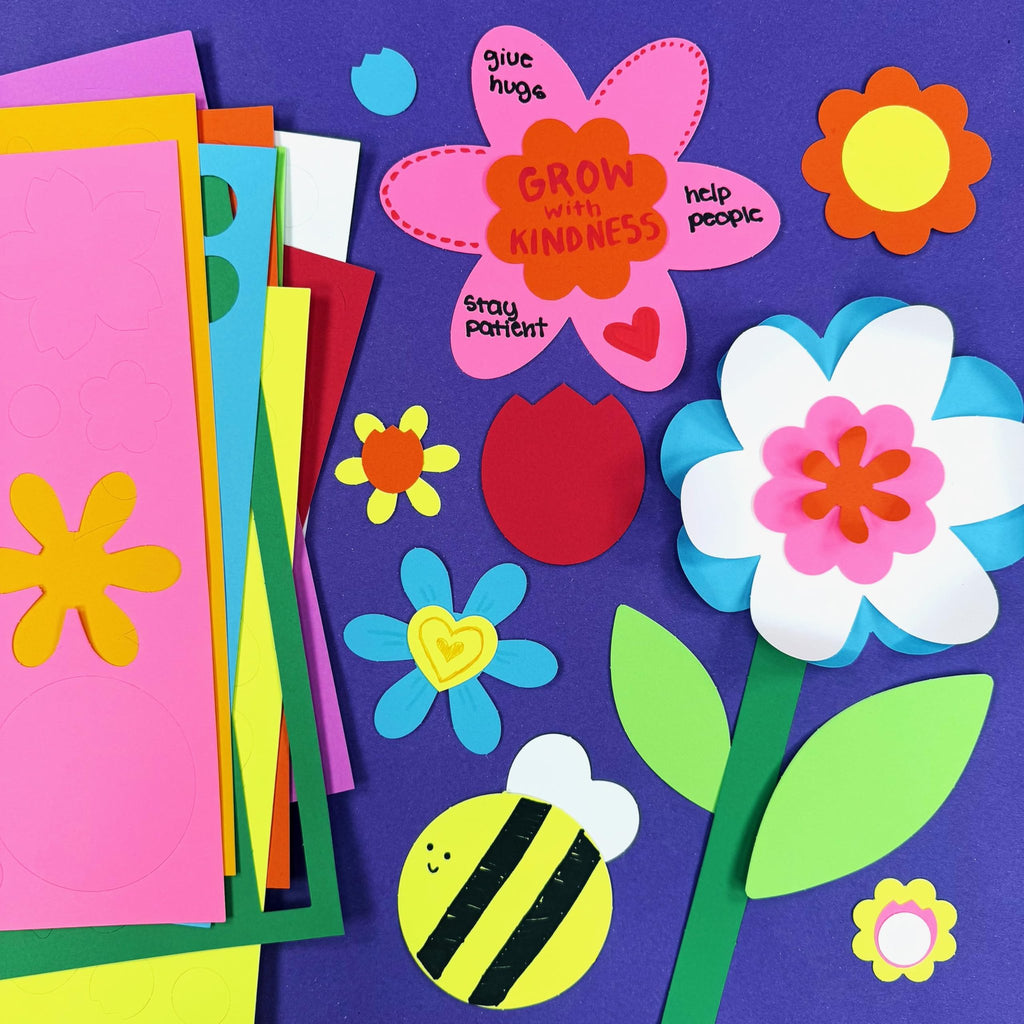 Assorted colorful craft paper cutouts including flowers, leaves, and a bee, arranged on a purple background.