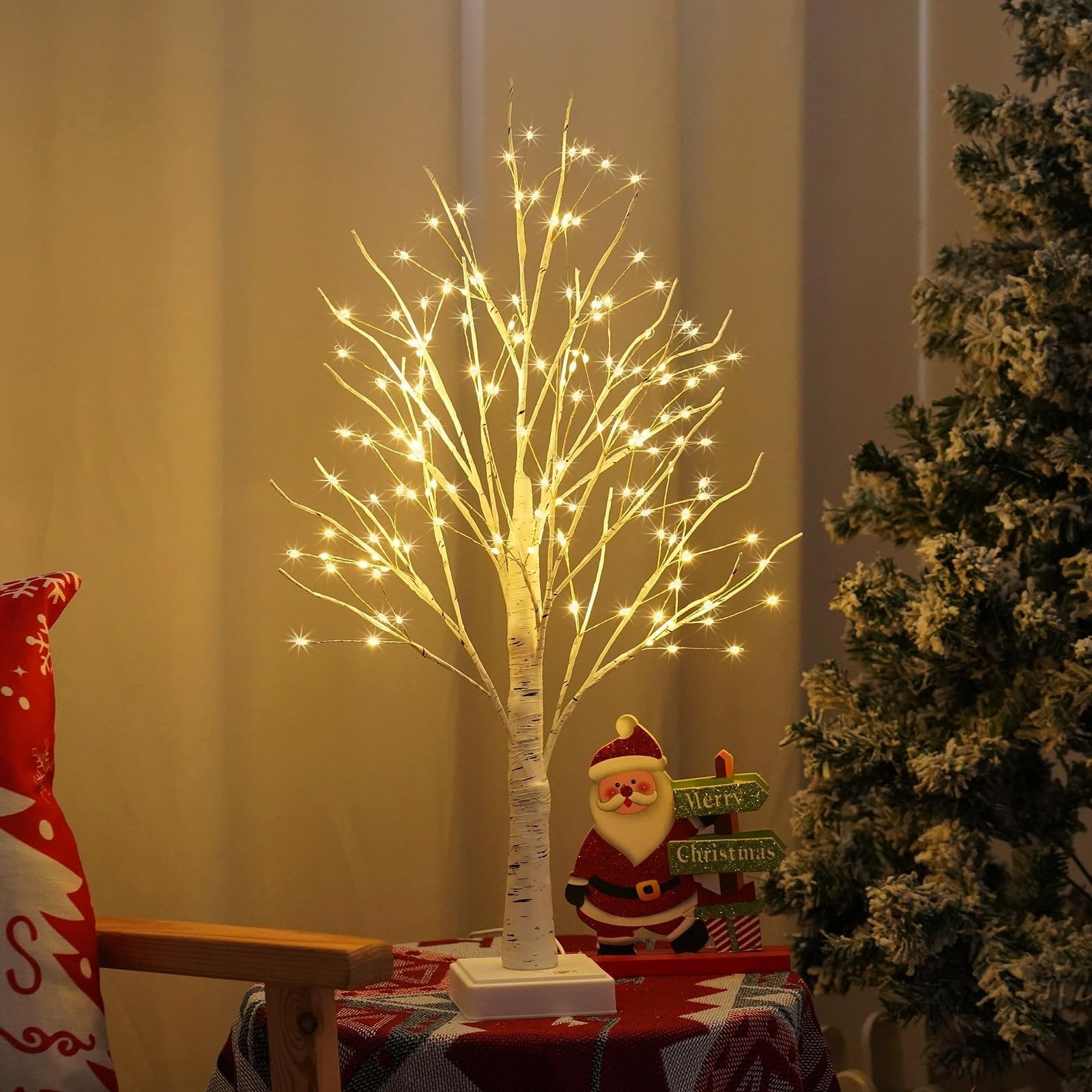 White birch Christmas tree with warm white LED lights and a Santa Claus decoration with Merry Christmas signs.