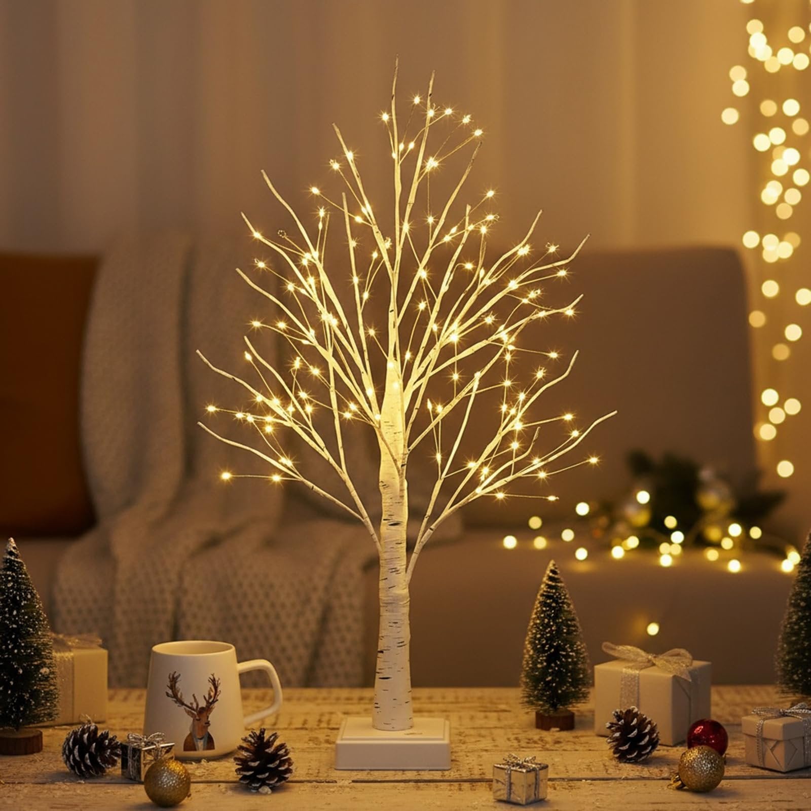 White birch LED Christmas tree with warm white lights on a wooden table with festive decor