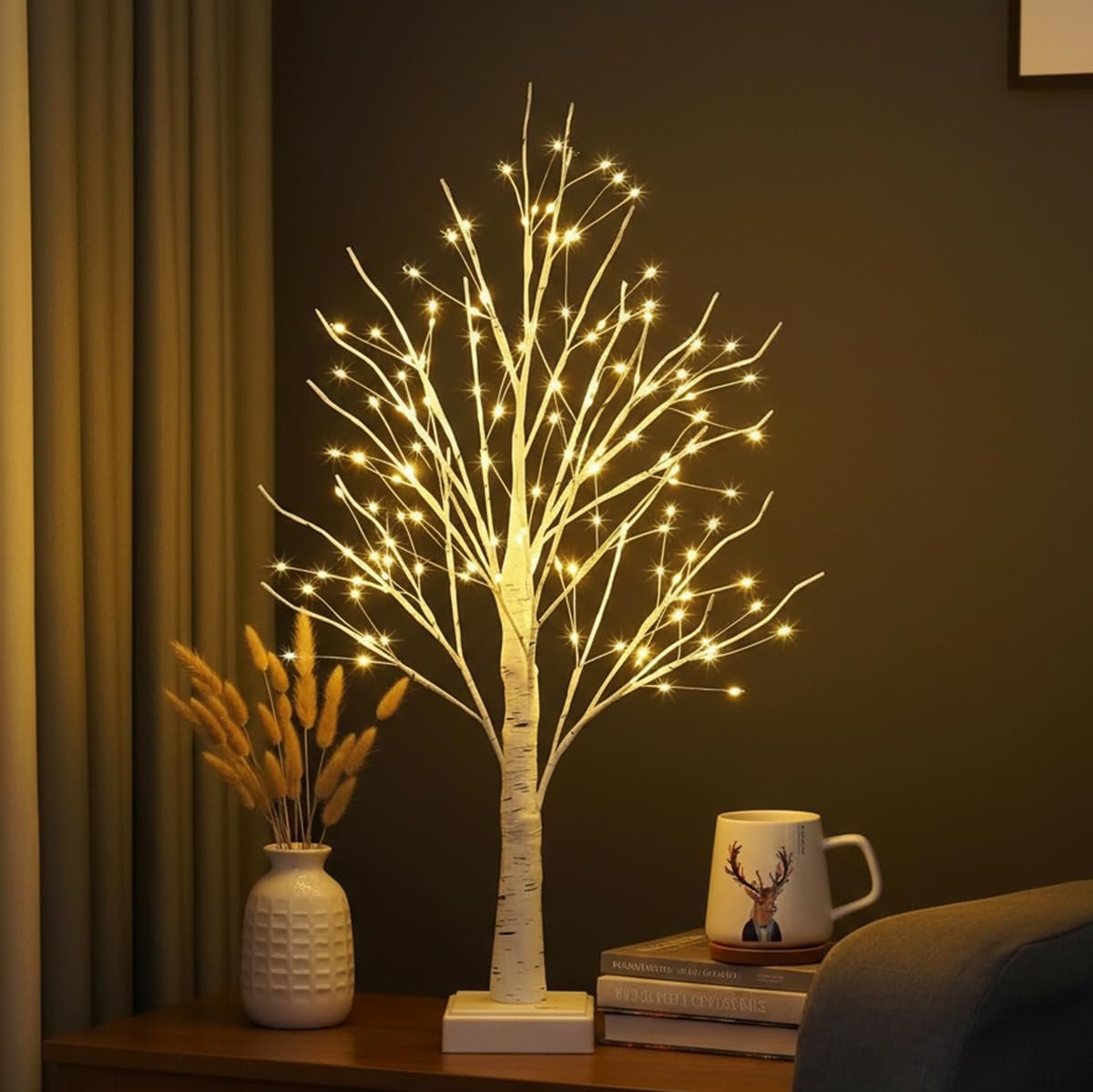 White birch tree with warm white LED lights on a table with a vase and mug