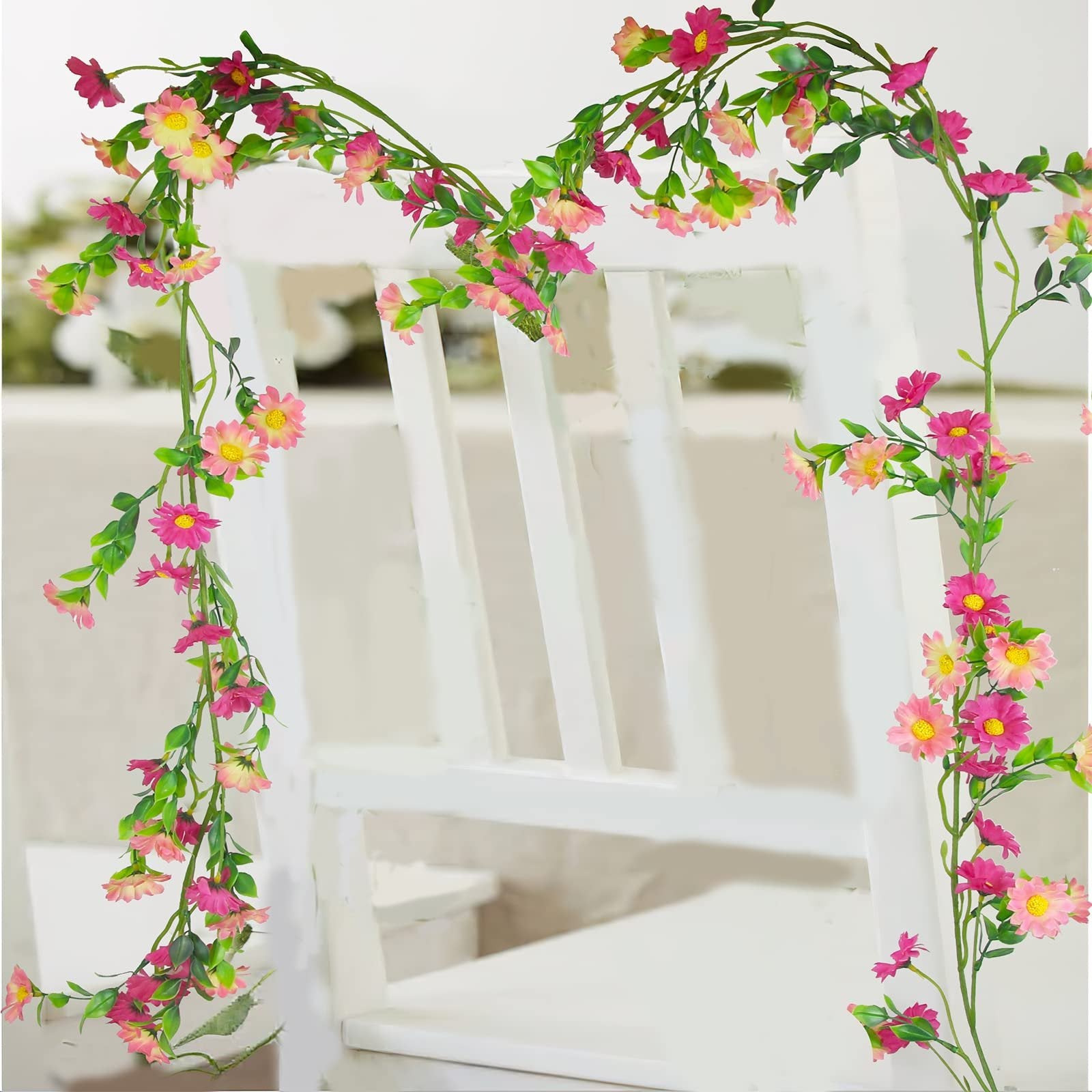 Artificial silk daisy vine garland with pink and yellow flowers and green leaves draped over a white chair.