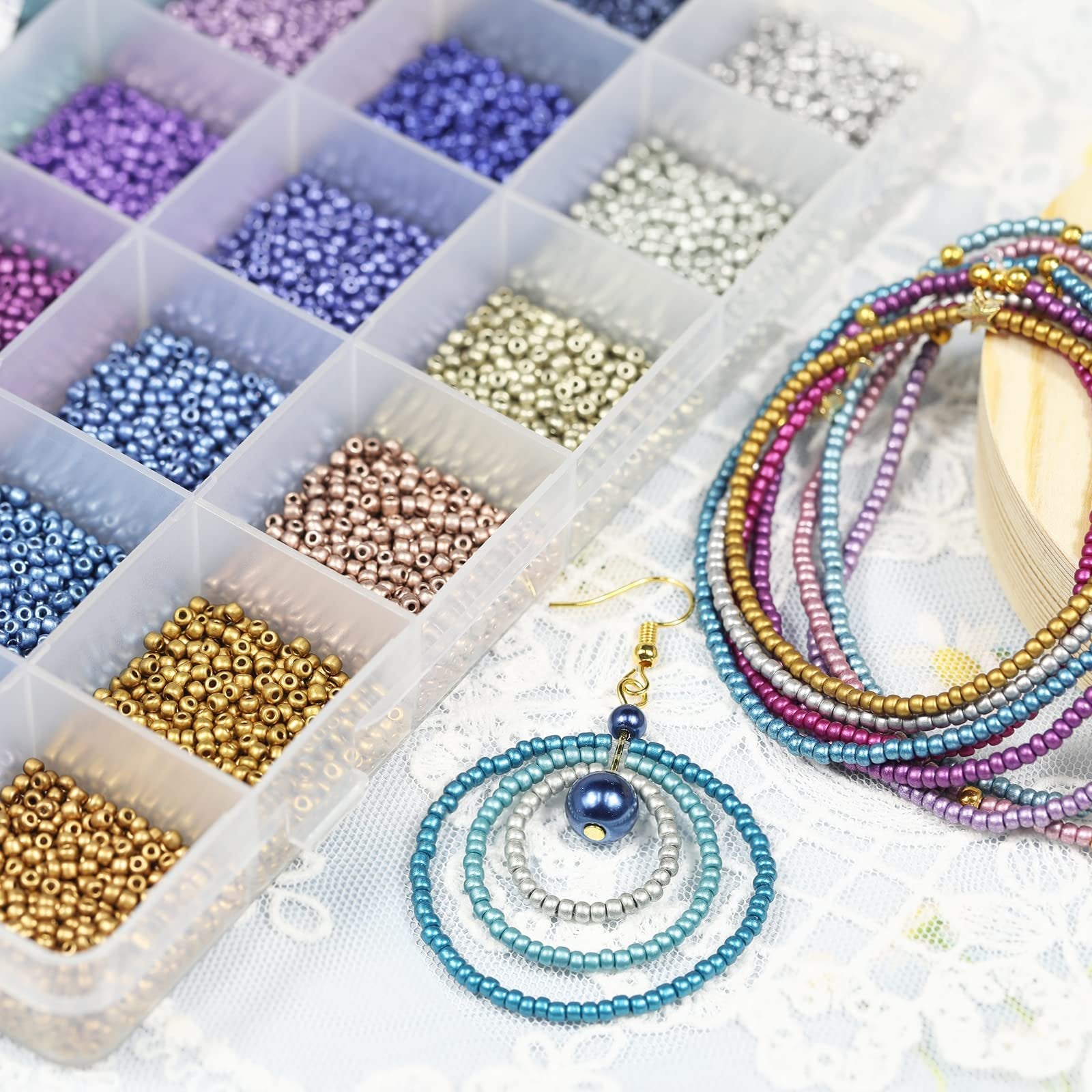 Assorted glass seed beads in a clear organizer box next to finished jewelry and an earring.