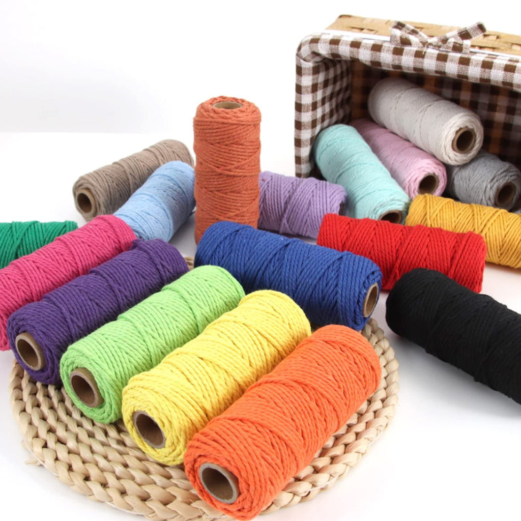 Assorted color rolls of 2mm macrame cotton cord spilling from a basket and arranged on a woven mat.